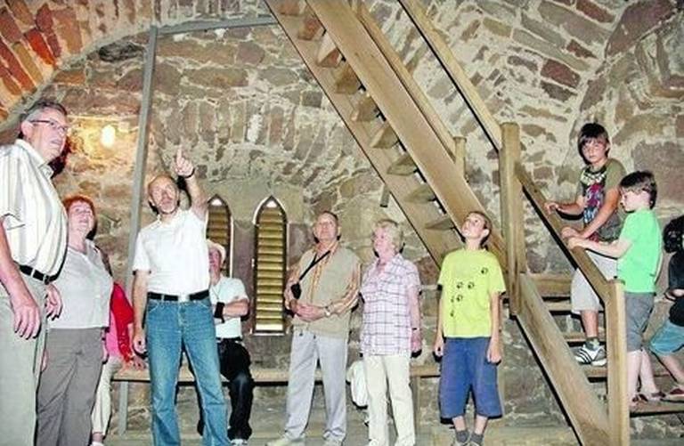 Im Glockenturm: Klaus Otto erläutert den Besuchern in der evangelischen Kirche Balhorn die historischen Hintergründe und die Baulichkeiten. Foto: zek